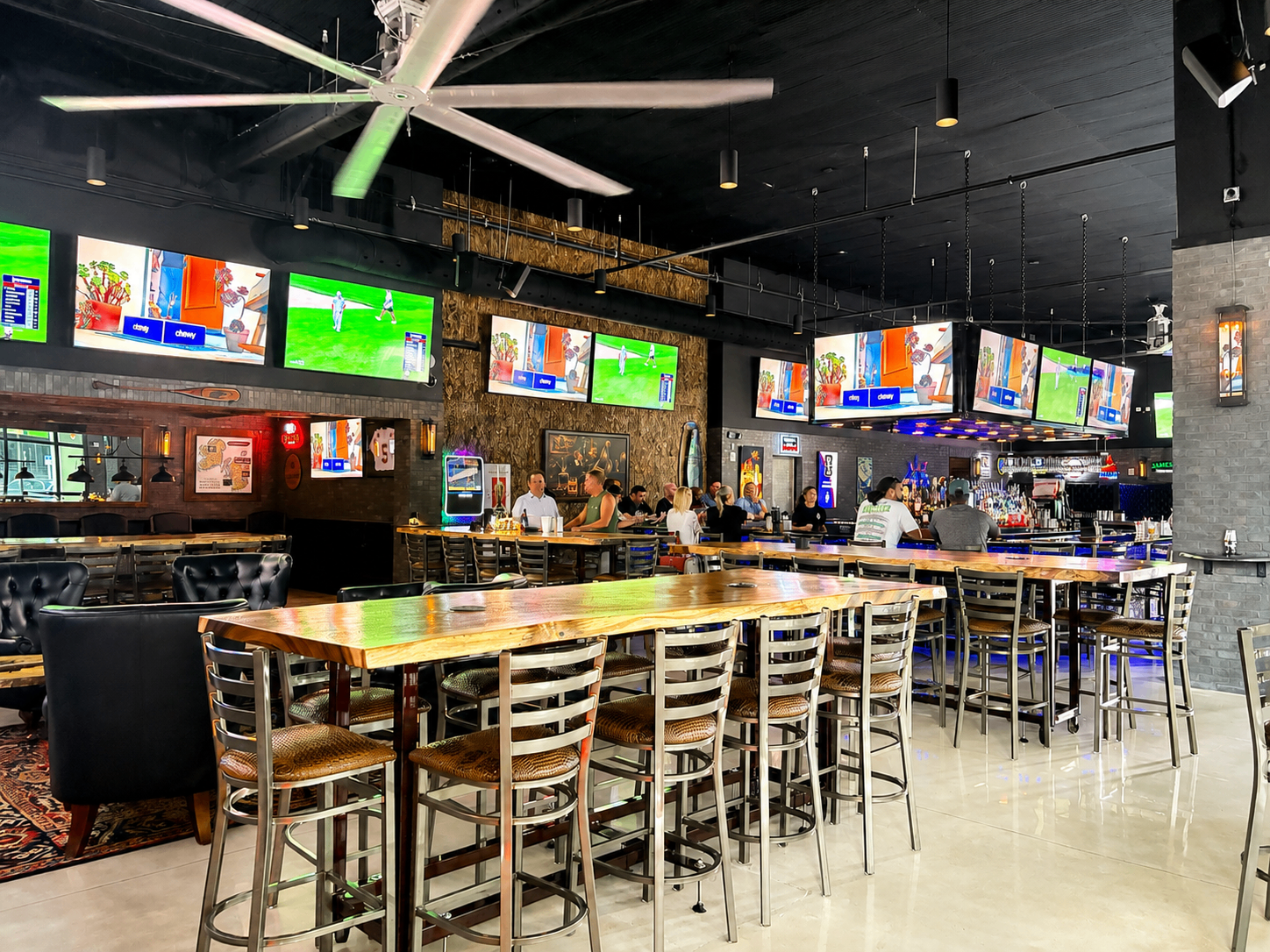 Main hall with big fan, live-edge high tops, and TVs all around