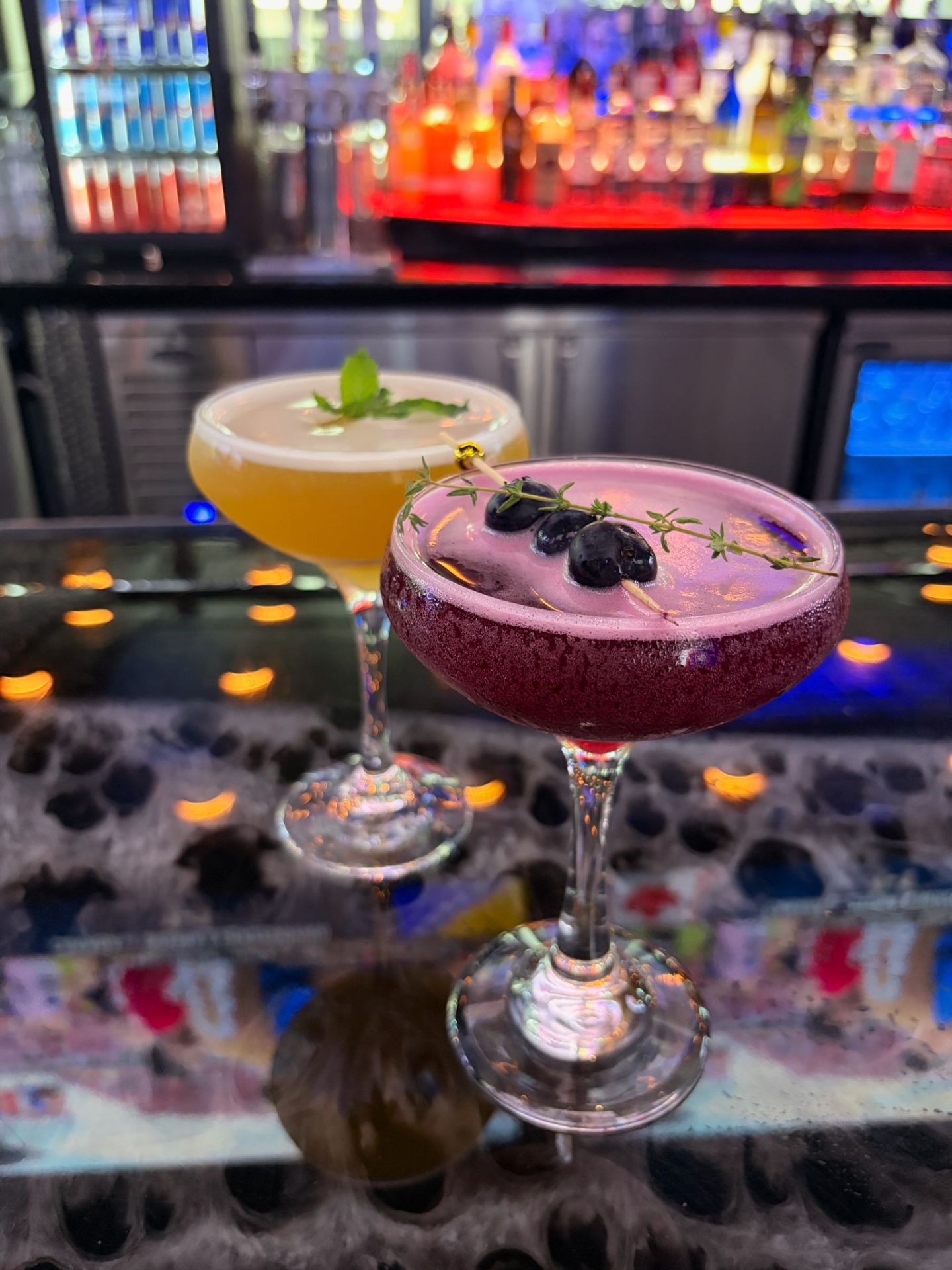 Blueberry-thyme and citrus coupe cocktails on the bar rail