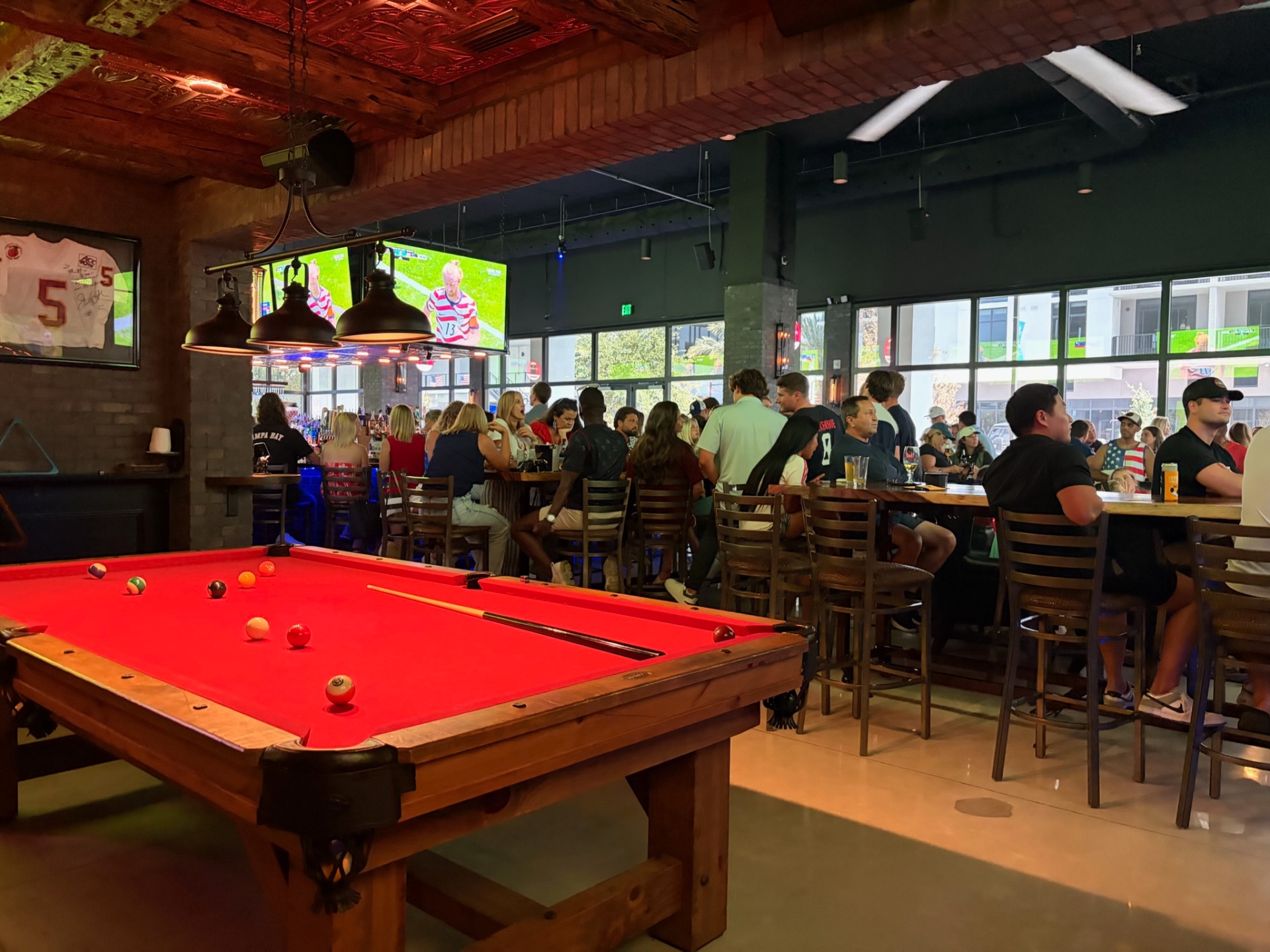 Pool table with a packed bar behind it at Back Bar