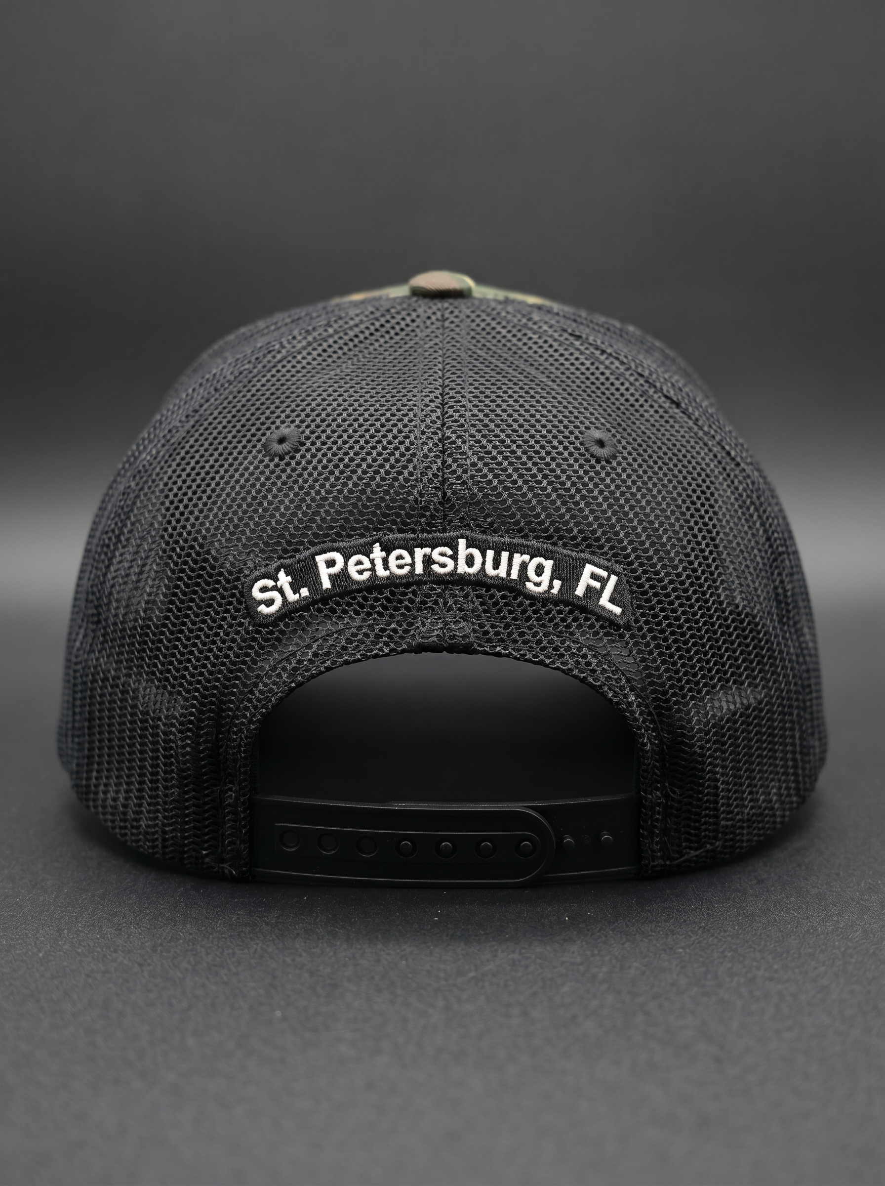 Back of the camo Back Bar trucker hat with 'St. Petersburg, FL' embroidery