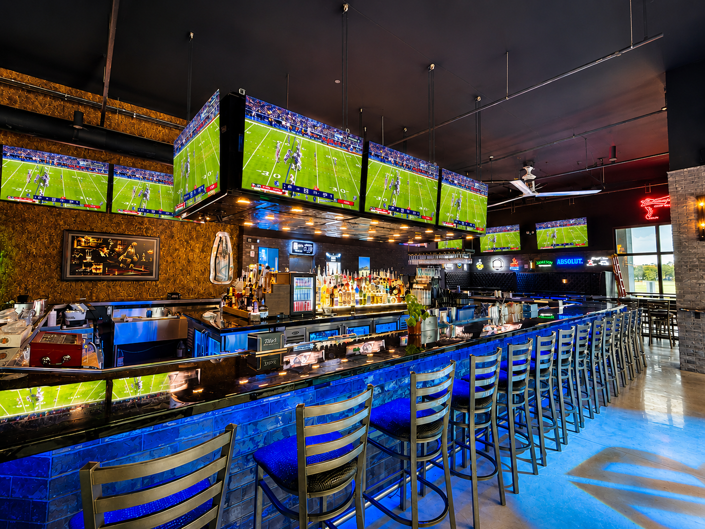 Full venue interior at Back Bar with bar seating, wall-to-wall TVs, and bottle display