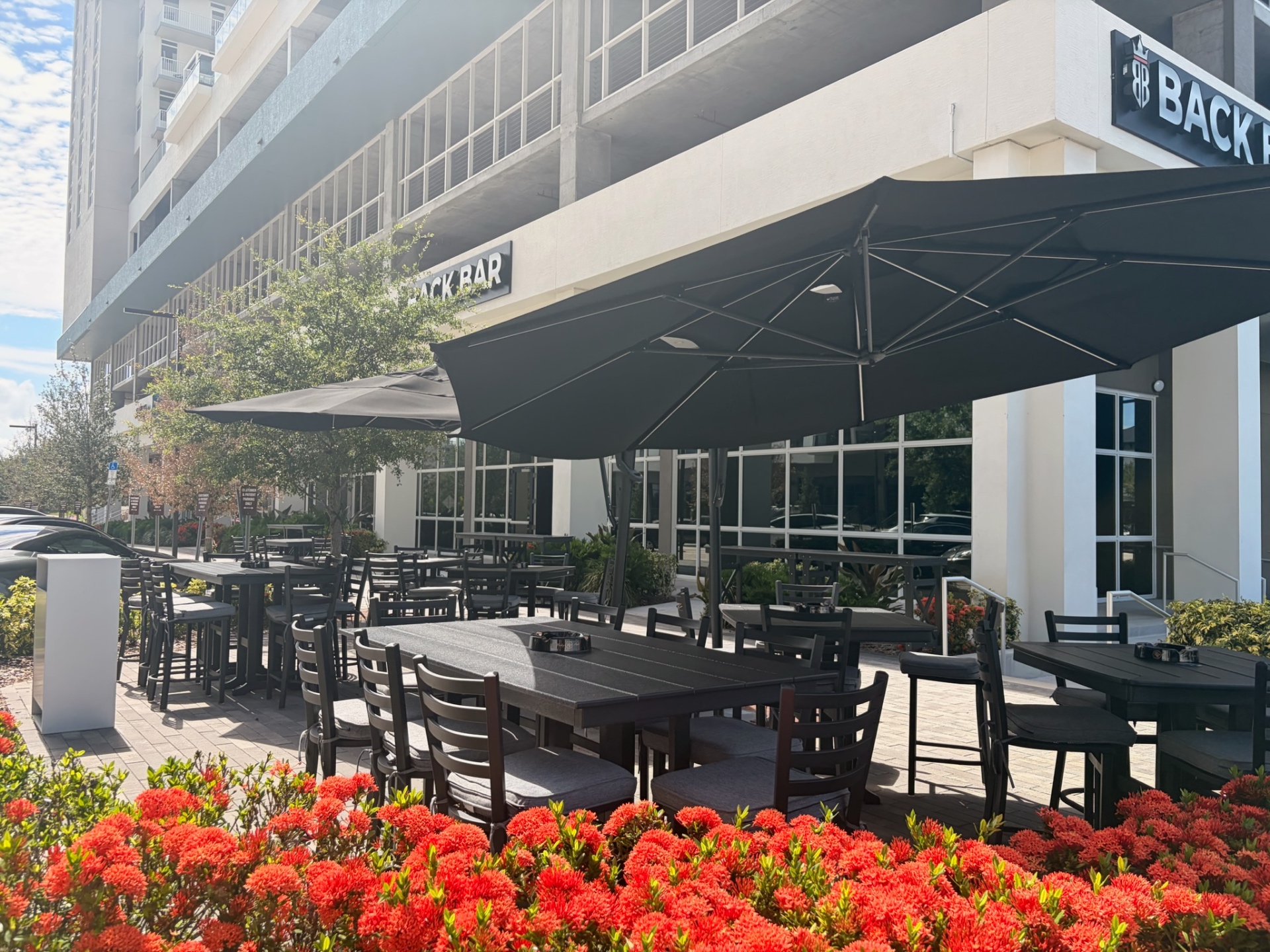 Back Bar patio with high-top tables, umbrellas, and red flowers