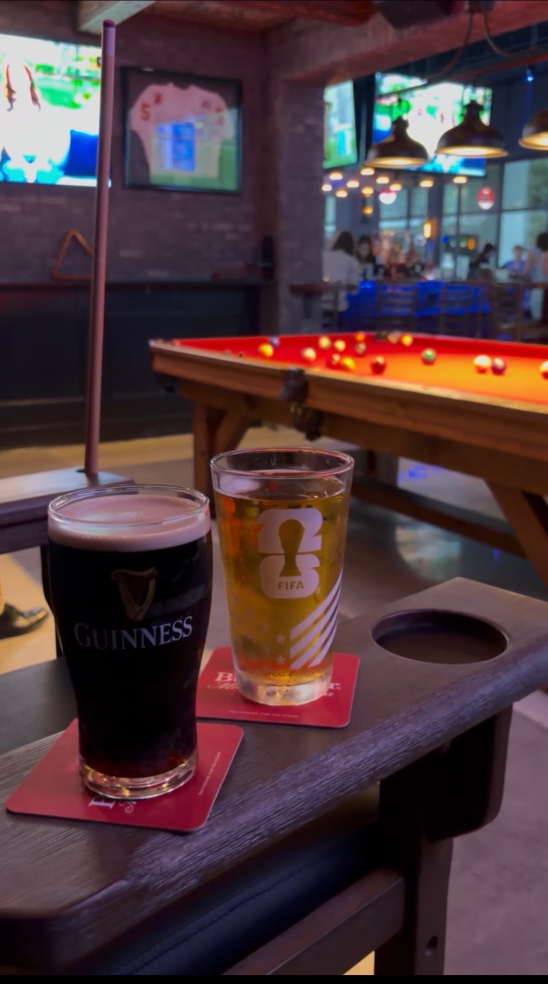 Guinness and a FIFA pint glass on a rail by the pool table