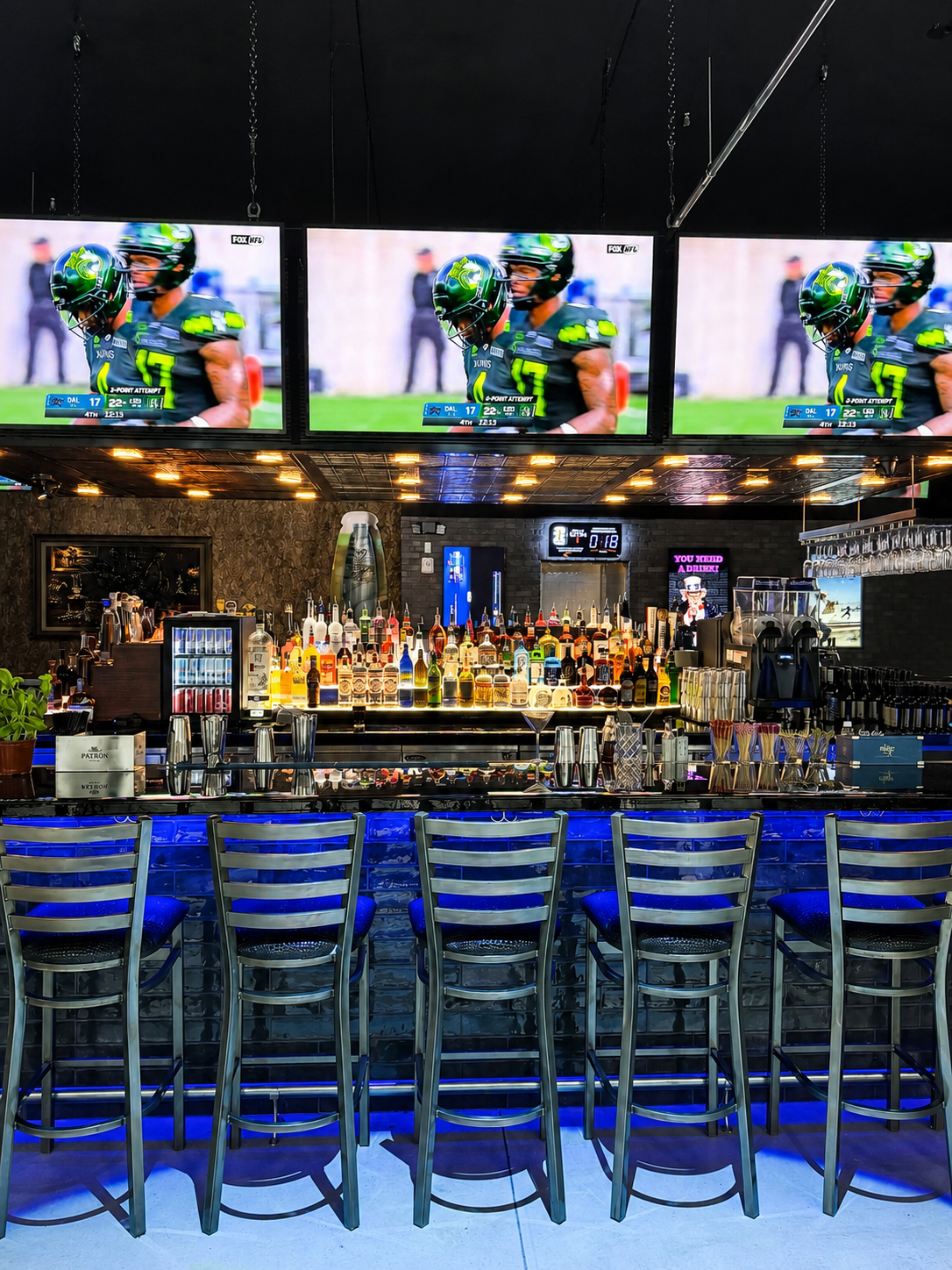 Back Bar with NFL game on the big screens, bar seating, and full bottle display